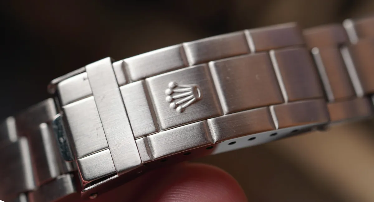 Close-up of a brushed stainless steel Rolex watch bracelet clasp with the crown logo visible