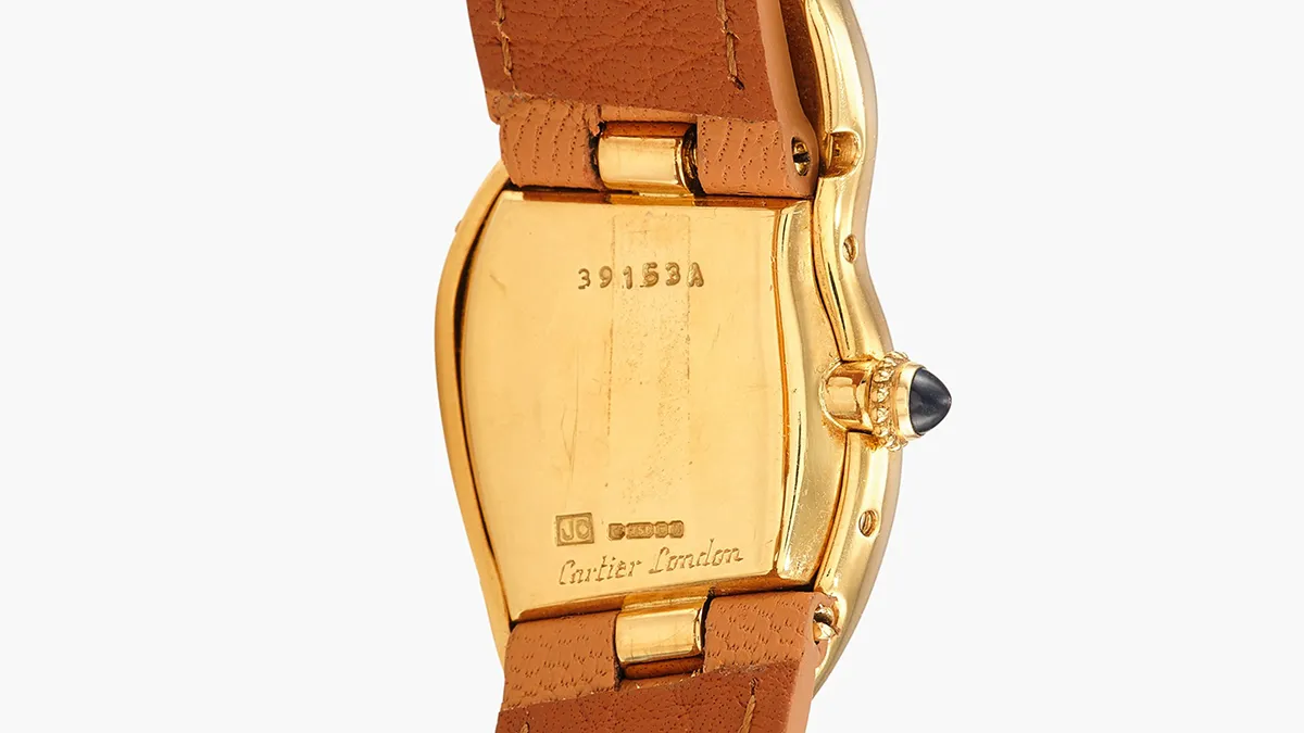 Back view of a gold Cartier watch with a brown leather strap, case back engraved with Cartier London and serial marks