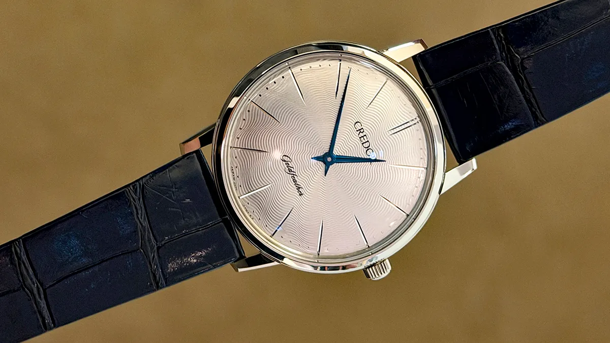 Classic analog wristwatch with a silver textured dial and blue hands on a black leather strap