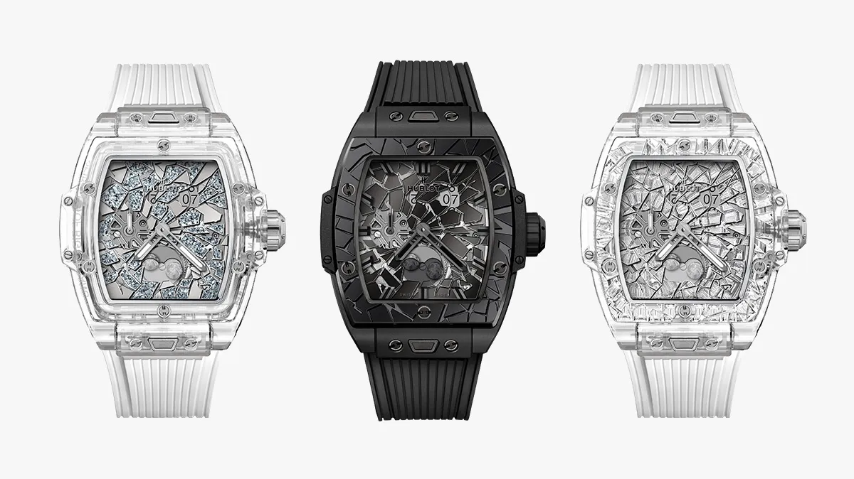 Three luxury Hublot watches with a squared, tonneau-shaped case and cracked-crystal dials: left and right in transparent/clear finishes with light-gray straps, center in all-black with a black strap.