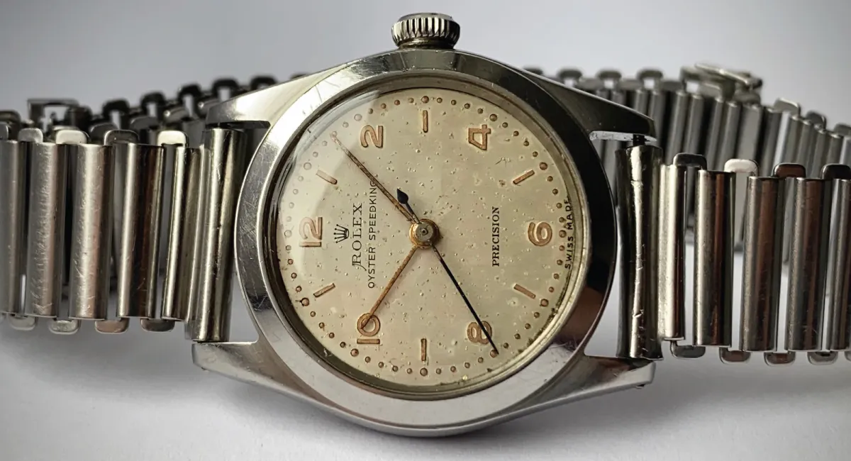 Close-up of a vintage Rolex Oyster Precision wristwatch with a cream dial and metal link bracelet.