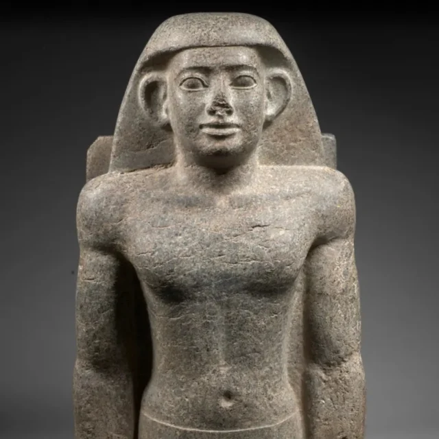 Ancient Egyptian relief: two figures facing each other on a carved stone with hieroglyphs above and an offering table between them.
