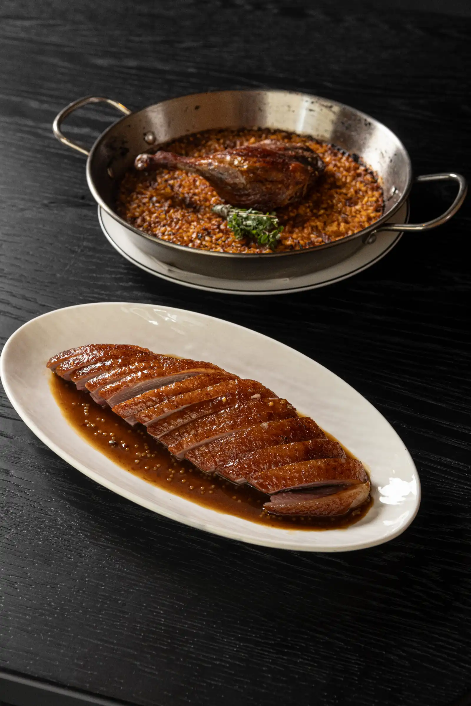 Sliced roasted duck with brown sauce on a white oval plate