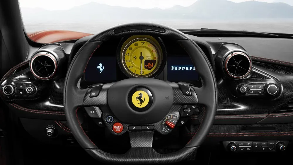 Close-up of a Ferrari cockpit: steering wheel with yellow prancing horse emblem, digital gauges, and carbon fiber dashboard.