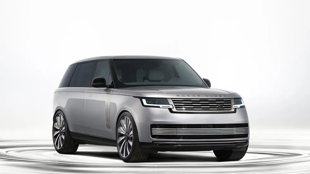 Silver Range Rover SUV in a bright studio setting, shown in a front three-quarter view with large alloy wheels.