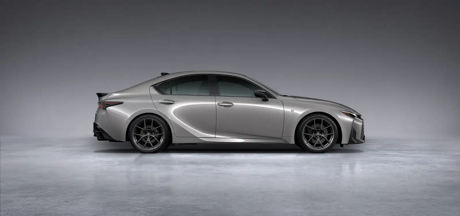 Side view of a silver luxury sedan with dark alloy wheels in a gray studio setting.