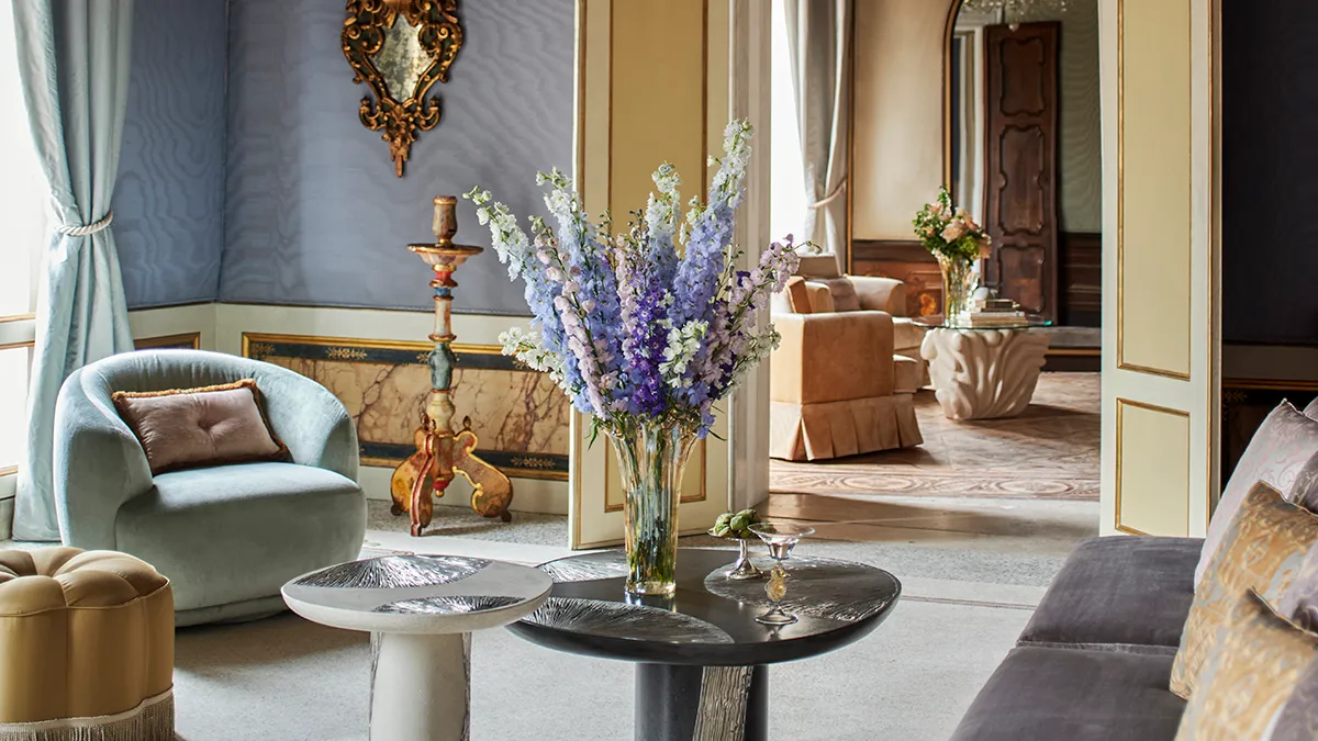 Luxurious living room with pastel blue walls and a glass vase of purple lavender on a round black coffee table.