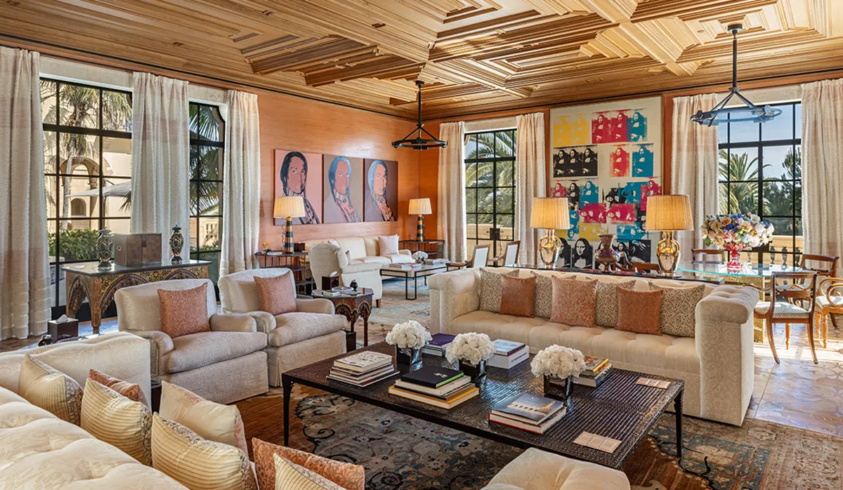 Elegant upscale living room with cream sofas, a dark coffee table, and a carved wooden ceiling.
