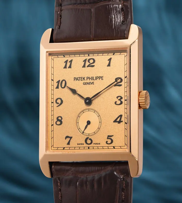 Gold rectangular wristwatch with cream dial, black numerals, and brown leather strap; Patek Philippe branding visible on dial.