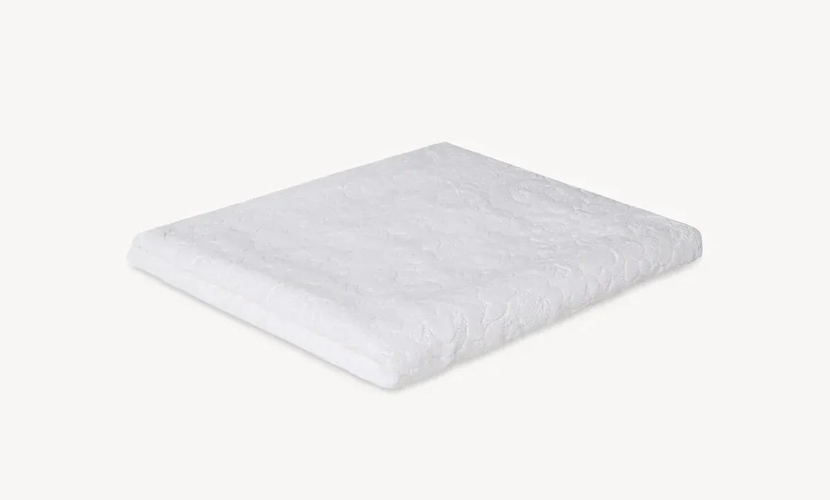 White quilted mattress cover folded into a square on a light background