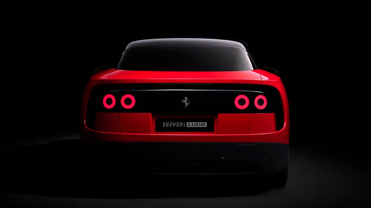 Rear view of a red Ferrari in darkness, with four circular taillights lit and a black rear panel bearing the Ferrari logo.