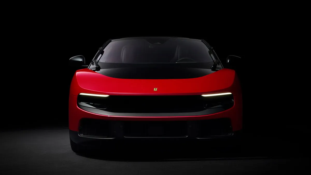 Front view of a red Ferrari sports car in a dark studio, headlights on, black hood and low aerodynamic design.