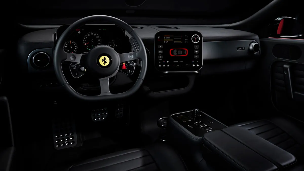 Inner view of a luxury sports car cockpit with a prominent steering wheel featuring a yellow Ferrari emblem and a large digital cluster behind it, plus a central touchscreen infotainment panel