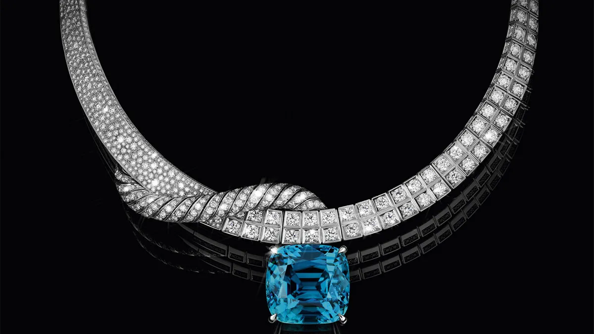 Diamond necklace with a large blue gemstone pendant on a black background.