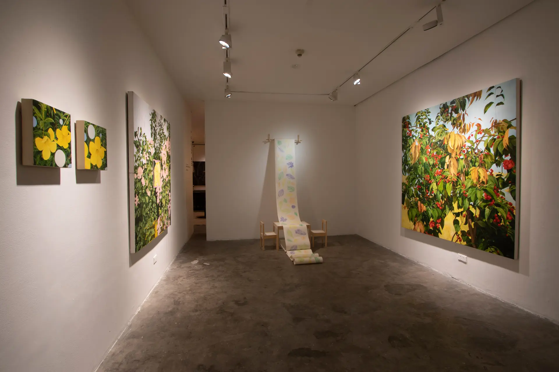 White-walled art gallery with large botanical paintings on both sides and a central hanging floral scroll installation.