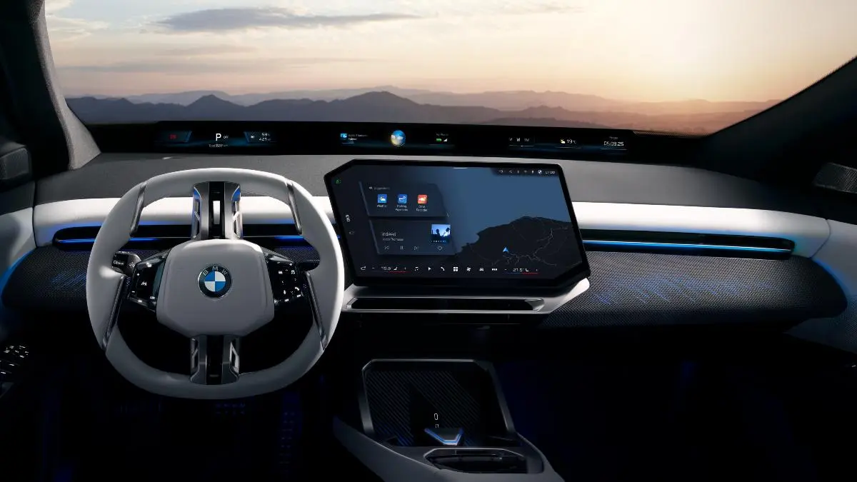 Futuristic BMW cockpit with a large tablet-style central screen, circular steering wheel, and ambient blue lighting against a sunset horizon outside the windshield, showcasing an advanced electric interior design.