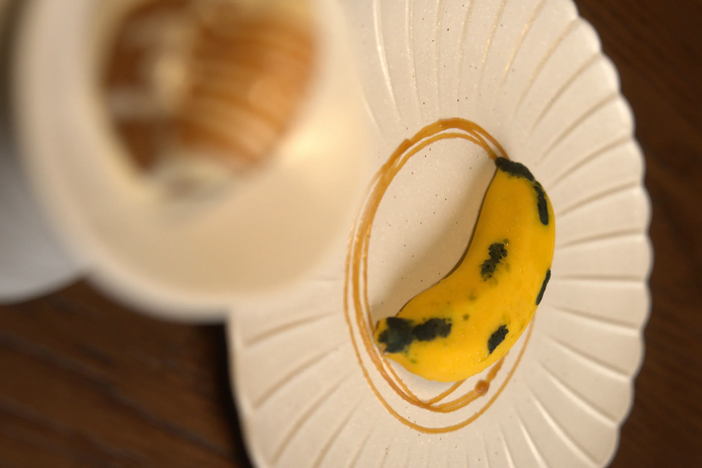 Close-up of a decorative white scalloped plate with an orange circular motif and a yellow accent with dark green speckles.