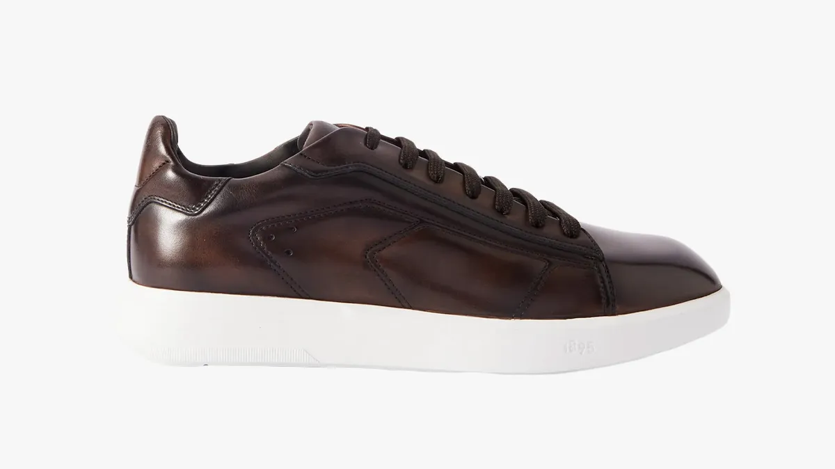 Brown leather low-profile sneaker with white sole and black laces, shown from the side and slightly angled.