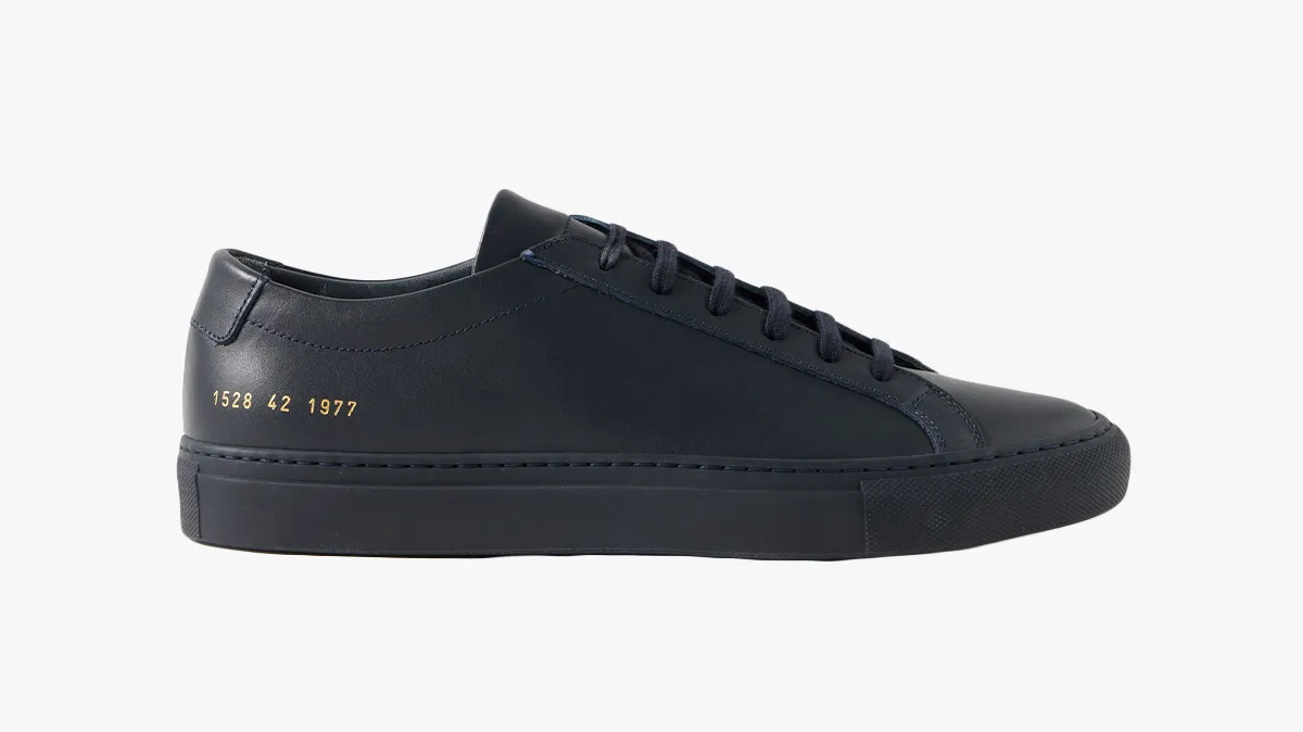 Navy blue low-top sneaker with a black sole and gold numbers along the heel.
