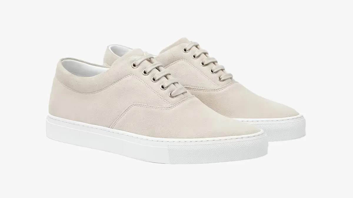 Beige suede sneakers with white rubber sole and lace-up front, side view on white background, pair of casual shoes