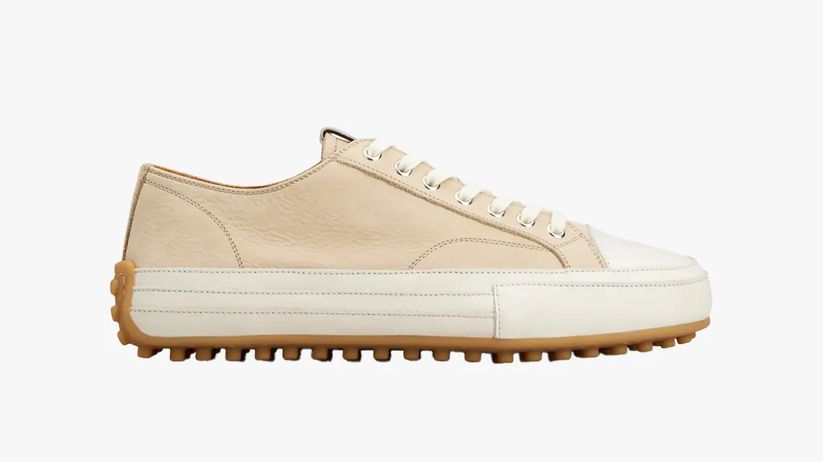 Beige leather sneaker with white toe cap and gum brown outsole on a white background.