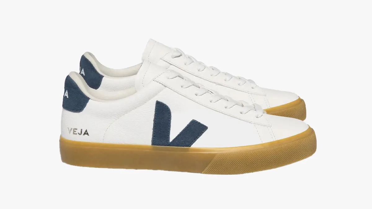 White Veja sneakers with blue heel accents and a tan gum sole, side V logo visible on the shoe side.