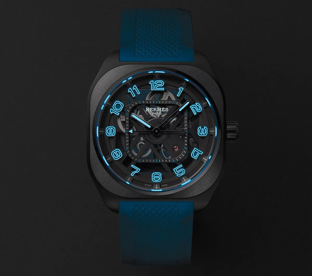 Skeleton-dial wristwatch with glowing blue numerals and blue strap, Hermes Paris, against a dark backdrop.