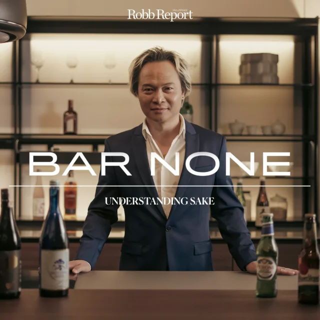 Promotional image of a man in a suit behind a bar with liquor bottles and bold white text 'BAR NONE' and 'UNDERSTANDING SAKE'.