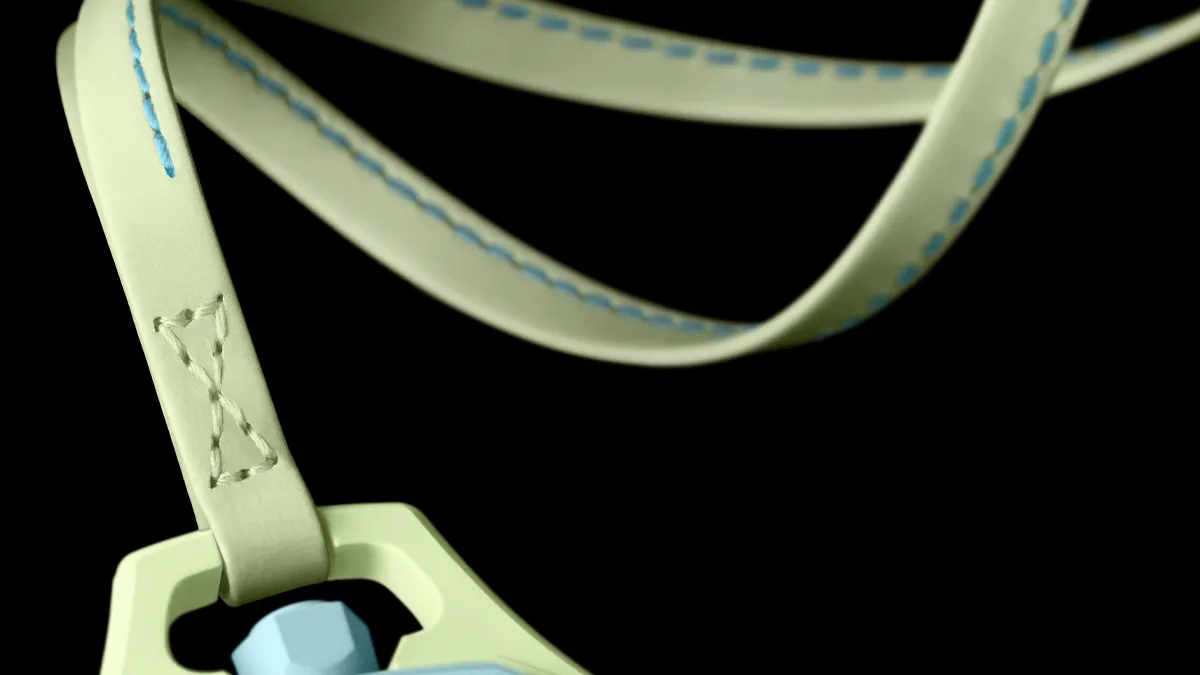 Close-up of a pale strap with blue stitching looping into a light-colored carabiner against a black background—safety gear detail. The strap on the Blaue Acht. Swatch