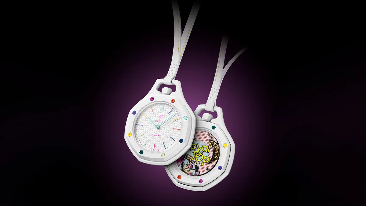 Two white pocket watches with rainbow gem accents on a dark background, one facing forward and the other showing its inner mechanism.