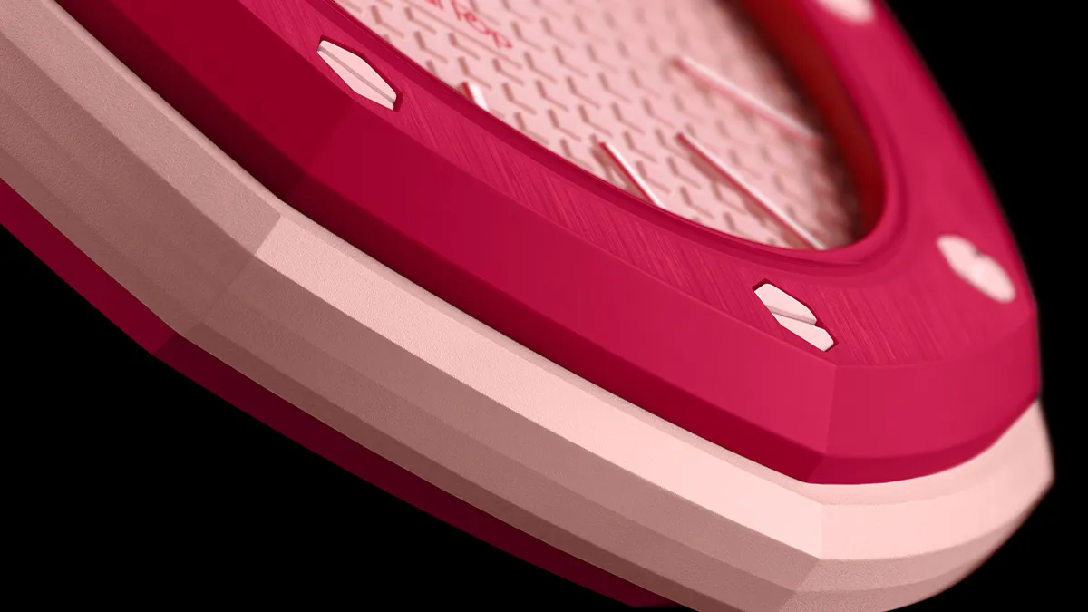 Close-up of a pink handheld device with a textured metallic surface and white accents, angled against a black background.
