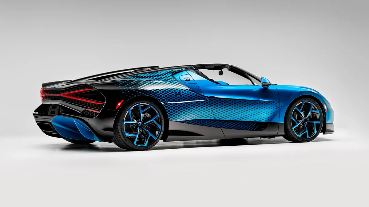 Side view of a blue and black convertible sports car with turquoise accents on a white studio background.