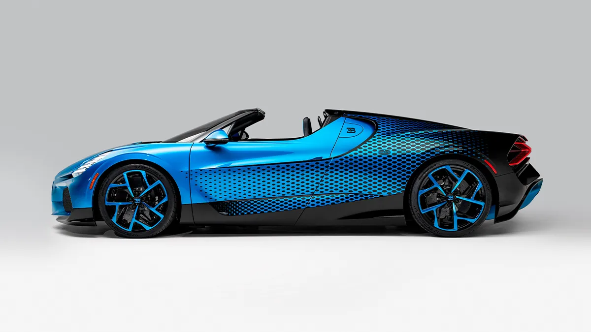 Blue convertible sports car in a studio setting with a blue and black dotted wrap and matching blue rims, side view showcasing low profile and sleek design.