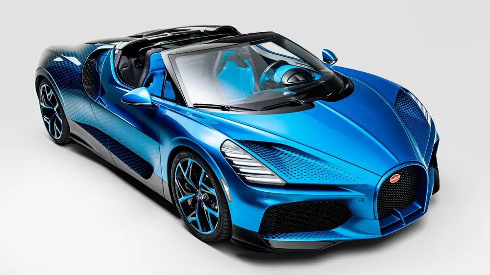 Blue luxury convertible sports car with open top viewed from a front-side angle, highlighting its sleek design.