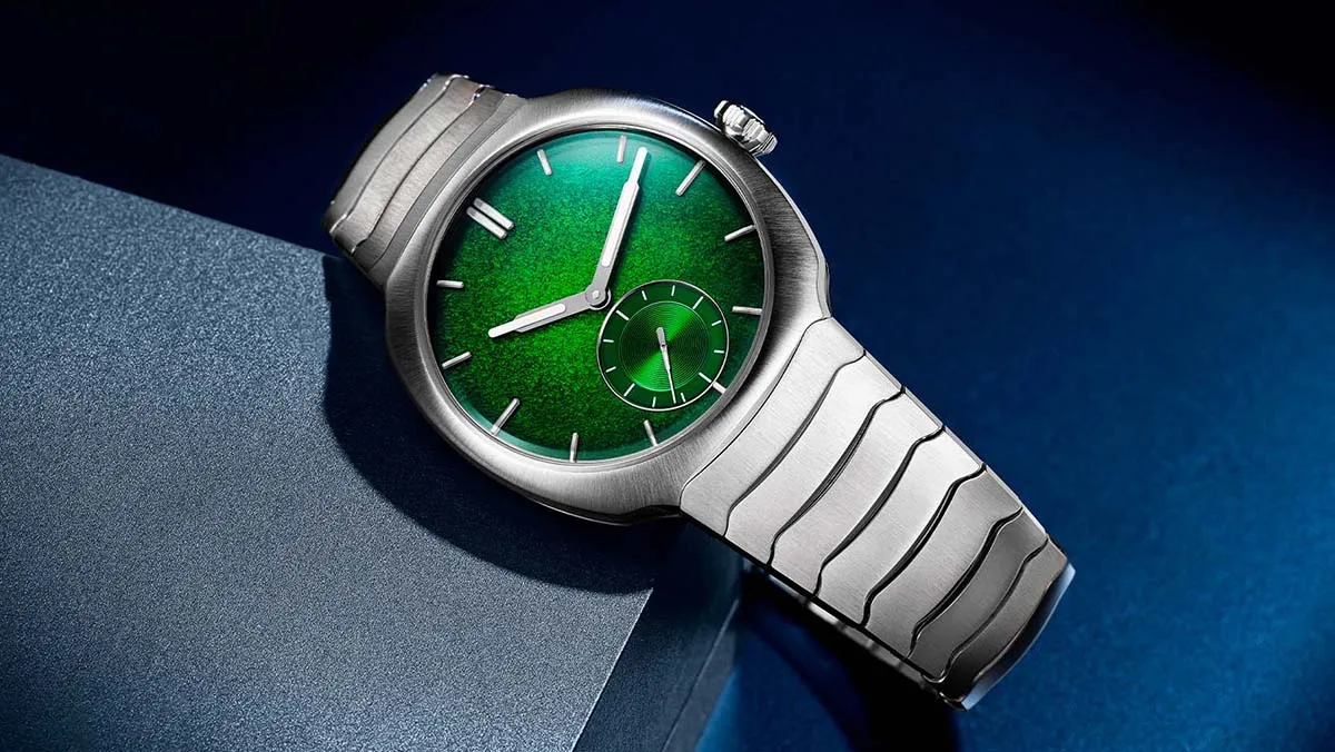 Stainless steel wristwatch with a vibrant green dial on a blue background, resting on a textured surface.