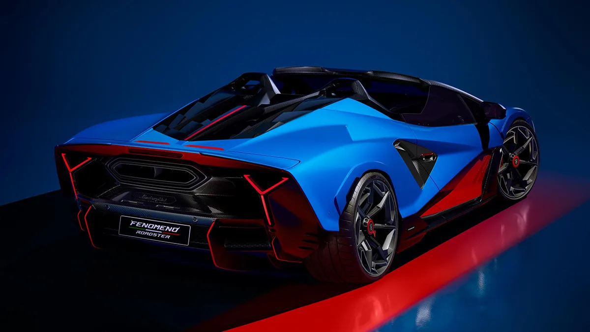 Rear three-quarter view of a blue and red futuristic sports car on a dark blue backdrop, with angular panels and glowing taillights.