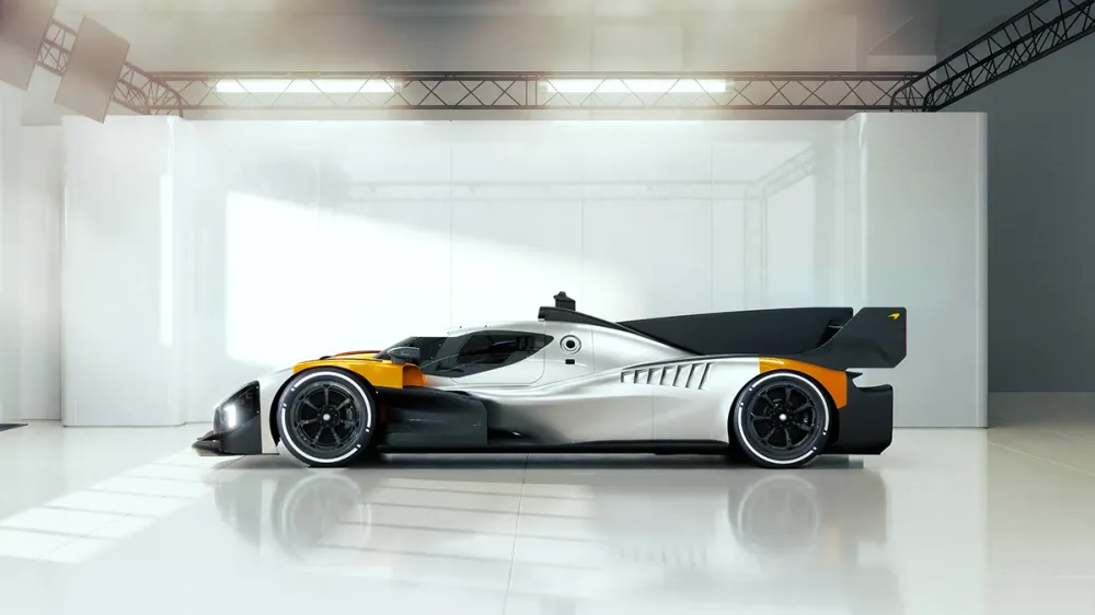 Silver and black high-performance race car with orange accents parked in a bright white studio.