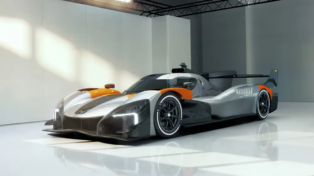 Futuristic silver and orange race car in a bright white studio showroom in side view.