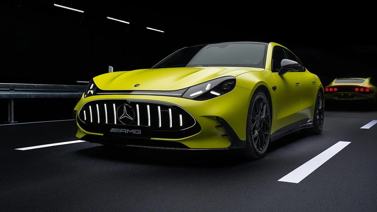 Front three-quarter view of a bright yellow Mercedes‑AMG sports car in a dark tunnel, with another yellow car visible in the background.
