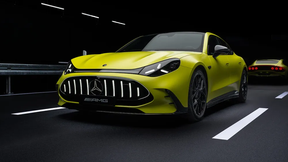 Front view of a bright yellow Mercedes-AMG sports car in a dark tunnel, with a second car in the background.