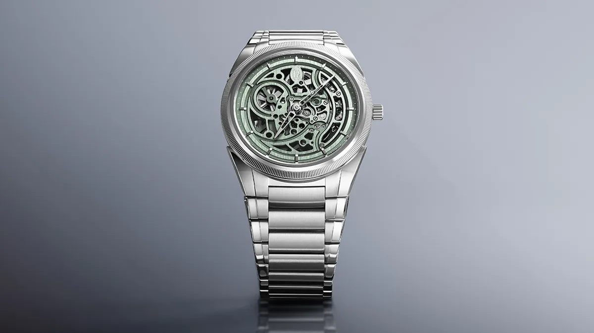 Silver skeleton wristwatch with visible gears on a gradient gray background, head-on view on a metal bracelet accessory.