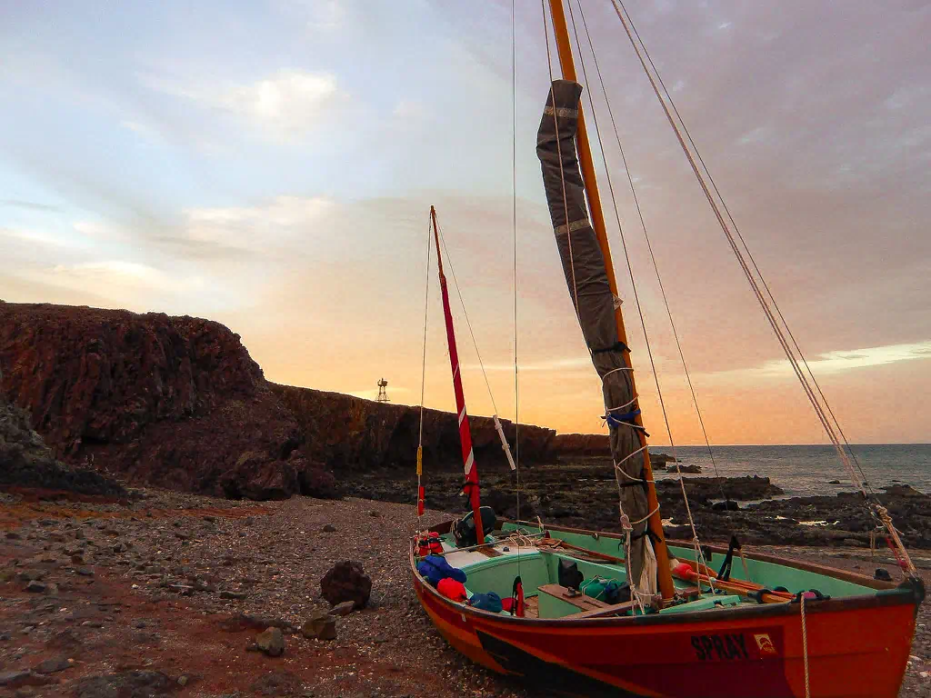 A beached sailboat on a windy day.